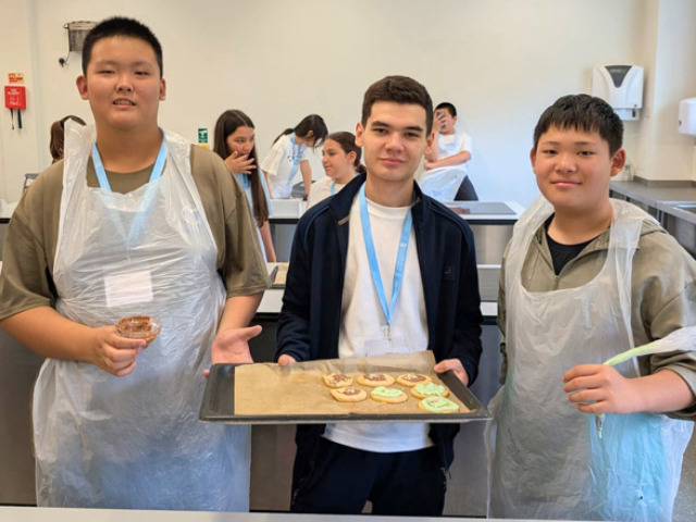 Three boys holding their tray of cookies