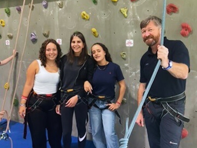Three girls and teacher standing beside the climbing frome